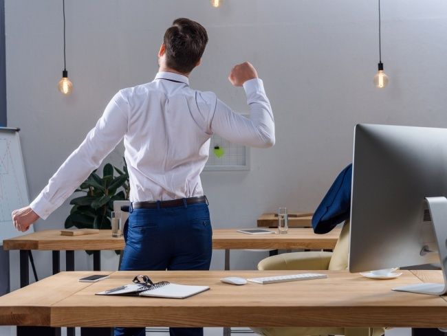 Person demonstrating a gentle standing stretch in a bright office environment